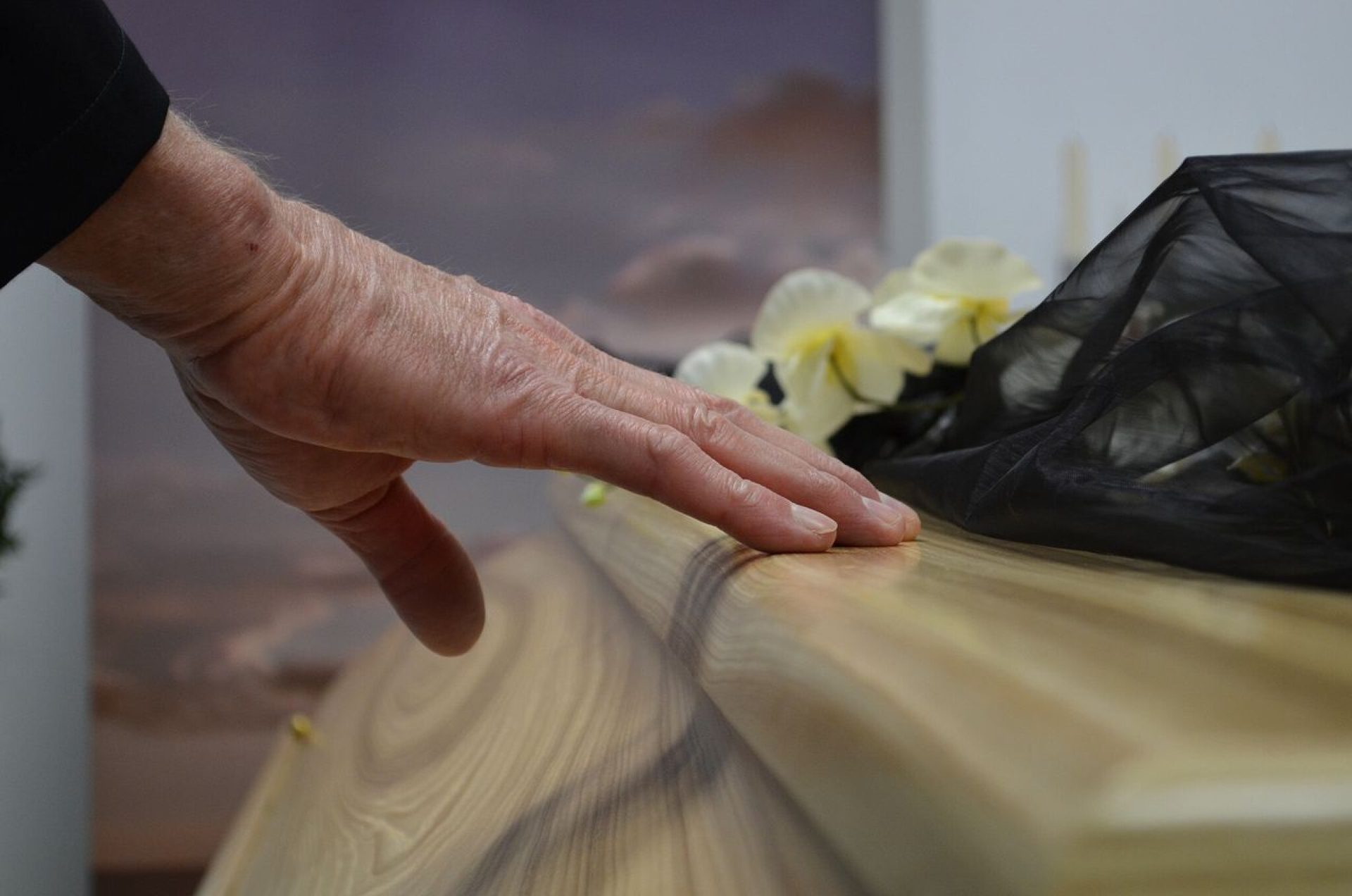 Een hand rust op een houten kist