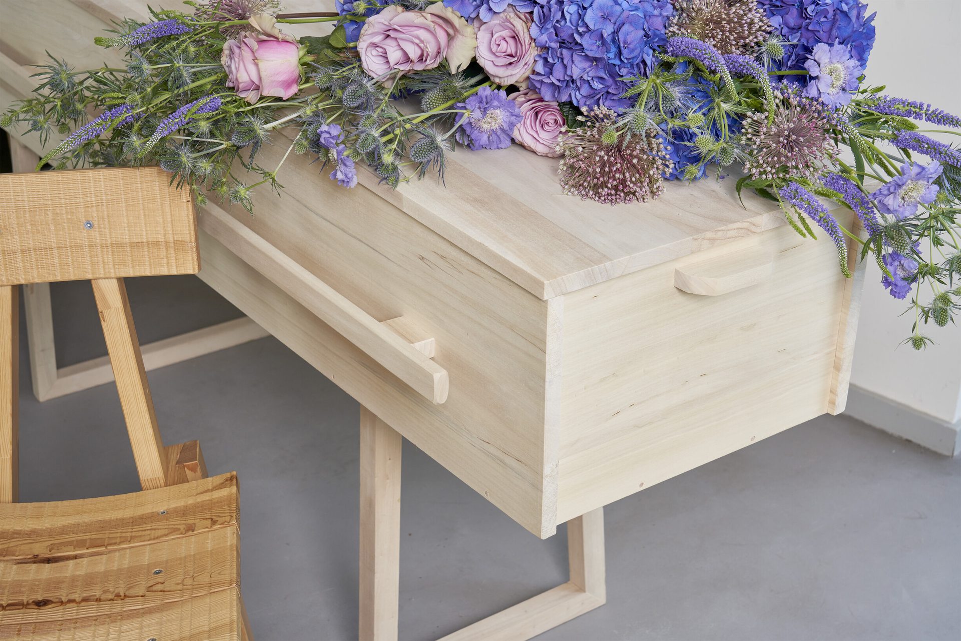 Een kist met blauwe bloemen, opgebaard tussen het groen